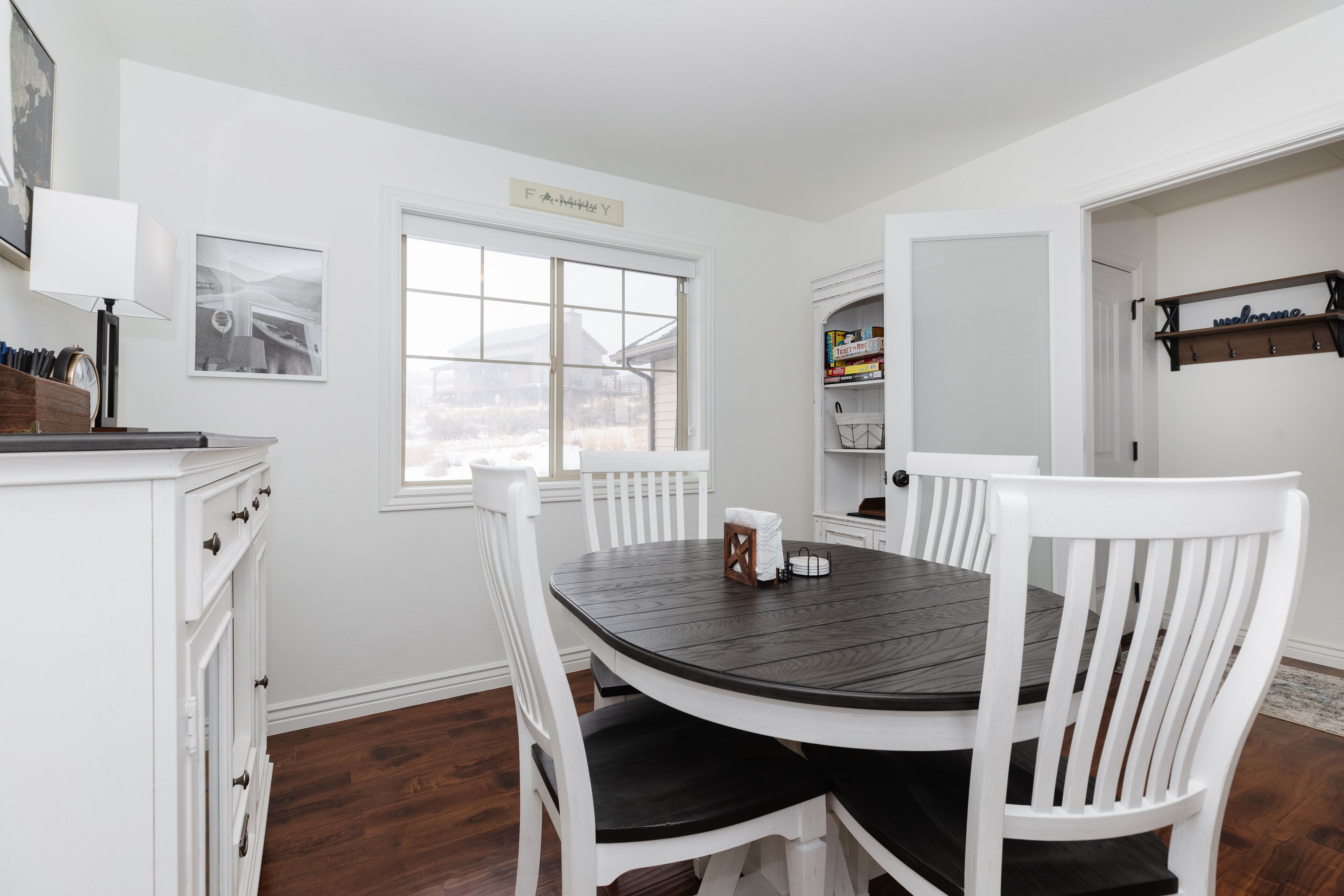 A dining room with a round table, white chairs, and a window.