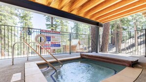 A hot tub with a wooden ceiling and a metal railing, surrounded by a natural outdoor setting.