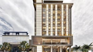 Un hotel moderno de varios pisos con un atrio central, balcones y una zona de estacionamiento.