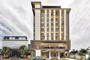 Un hotel moderno de varios pisos con un atrio central, balcones y una zona de estacionamiento.