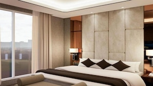 Habitación de hotel moderna con una cama grande, un sofá, una mesita de noche y vistas a la ciudad.