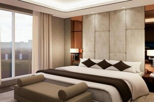 Habitación de hotel moderna con una cama grande, un sofá, una mesita de noche y vistas a la ciudad.