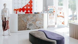 Una moderna zona de recepción con mostrador de mármol, un gran reloj de pared y un área de descanso.