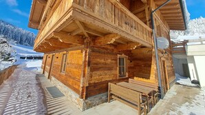 Eine Holzhütte mit Balkon, Satellitenschüssel und einer Bank vor der Tür.
