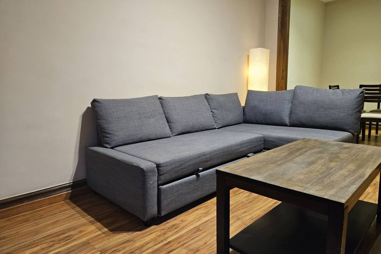 A modern living room with a grey sectional sofa, a wooden coffee table, and a tall floor lamp.