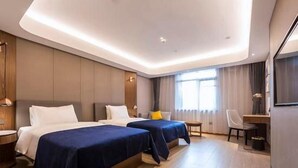 Une chambre d’hôtel avec deux lits, un bureau, une chaise et une grande fenêtre.