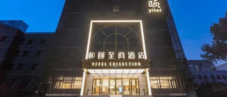 A hotel entrance with a modern design, featuring a prominent sign for 'Yitel Collection' and a staircase leading to the entrance.