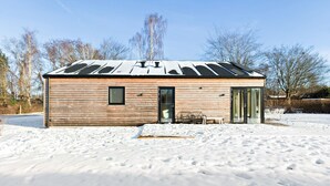 A small wooden cabin with a metal roof, a glass door, and a bench outside.