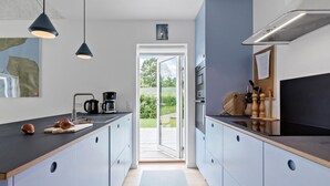 A modern kitchen with a central island, pendant lighting, and a view to the outdoors.