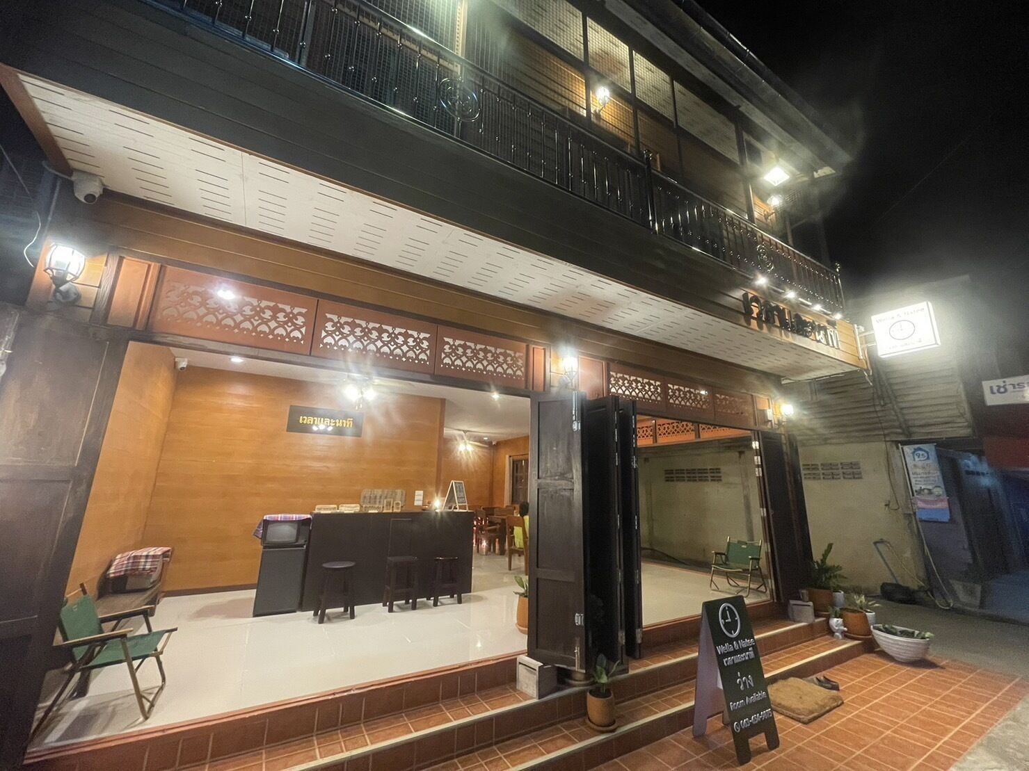 A hotel entrance with a reception desk, seating area, and a balcony.