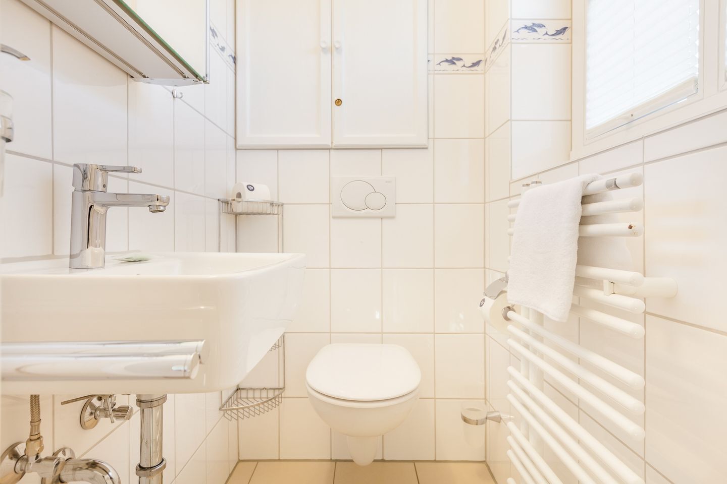 A small, clean bathroom with a white sink, toilet, and towel rack.
