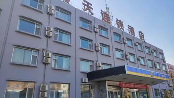 A multi-story building with air conditioning units, a lion statue, and a signboard.