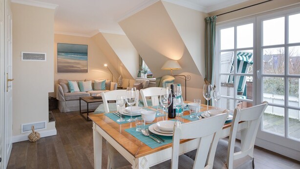 Un coin repas avec une table dressée pour quatre personnes, un canapé et un tableau accroché au mur.