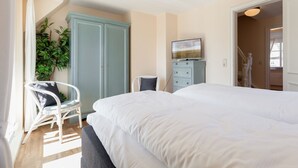 Ein Schlafzimmer mit einem großen Bett, einem Kleiderschrank, einem Fernseher und einem Sessel.