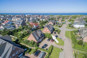 Vista aérea de una zona residencial con casas, una carretera y una masa de agua al fondo.