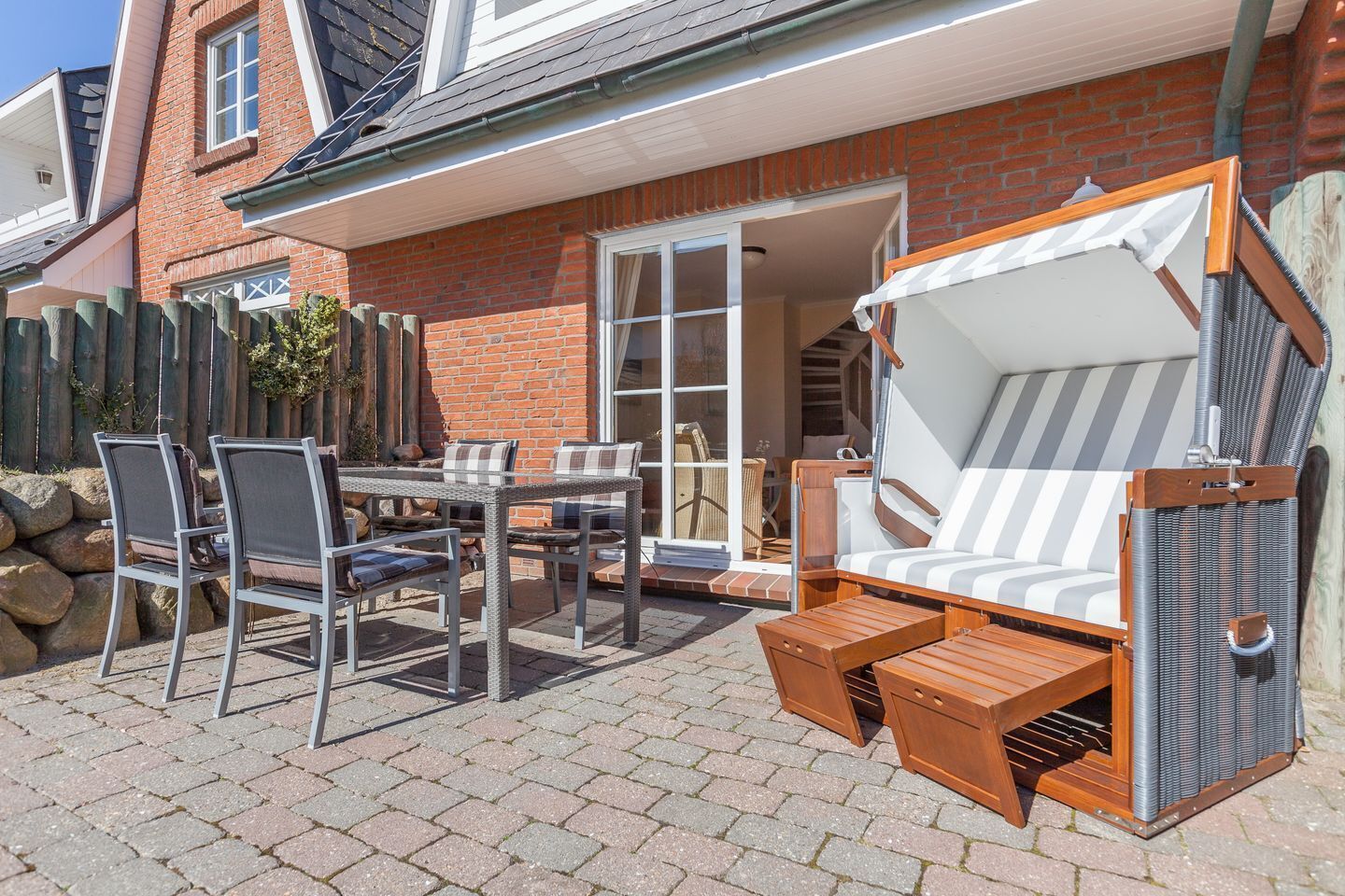 A patio with a table and chairs, a cushioned outdoor sofa, and a wooden deck.