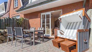 Eine Terrasse mit Tisch und Stühlen, einer gepolsterten Außenliege und einem Holzboden.