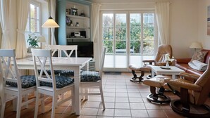 Ein Wohnzimmer mit Essbereich, einer Bücherwand, einem Sofa und einem Sessel.