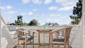 A small outdoor patio with a wooden table and two chairs, a bottle, and glasses on the table. - Friesenhörn, App. 4 Links - Dorfteich. Dünen. Viel Erholung (Wenningstedt-Braderup (Sylt))