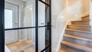 Un interior moderno con una escalera, un vidrio y un pasillo que lleva a una puerta.