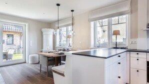 Una cocina moderna con una isla grande, luces colgantes y vistas al exterior.