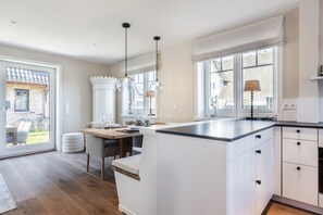 Et moderne køkken med en stor ø, hængende lamper og udsigt ud