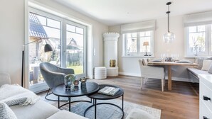 Amplia sala de estar con un ventanal, comedor con mesa de madera y una zona de estar acogedora con sofá y sillón.