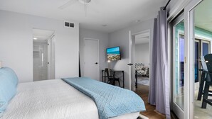 A bedroom with a bed, a television, a desk, and a view of the outdoors.