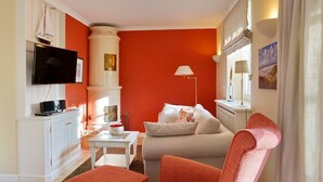 Ein Wohnzimmer mit einer Couch, Sesseln, einem Fernseher, einem Kamin und einer Wand mit einer Segelschiff-Dekoration.
