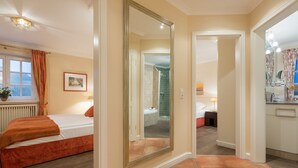 A bedroom with a bed, a large mirror, and a bathroom with a shower and sink. - Klingler's Hüs, App. 1 - Style Meets Fashion. Bestlage Zwischen Dünen und Dorfteich (Wenningstedt-Braderup (Sylt))