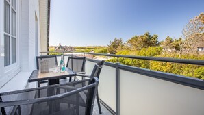 Een balkon met een tafel en stoelen, met uitzicht op een schilderachtig landschap met bomen en gebouwen.