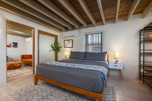 Une chambre à coucher avec un lit en bois, une table de chevet, une commode, une fenêtre et une étagère intégrée.