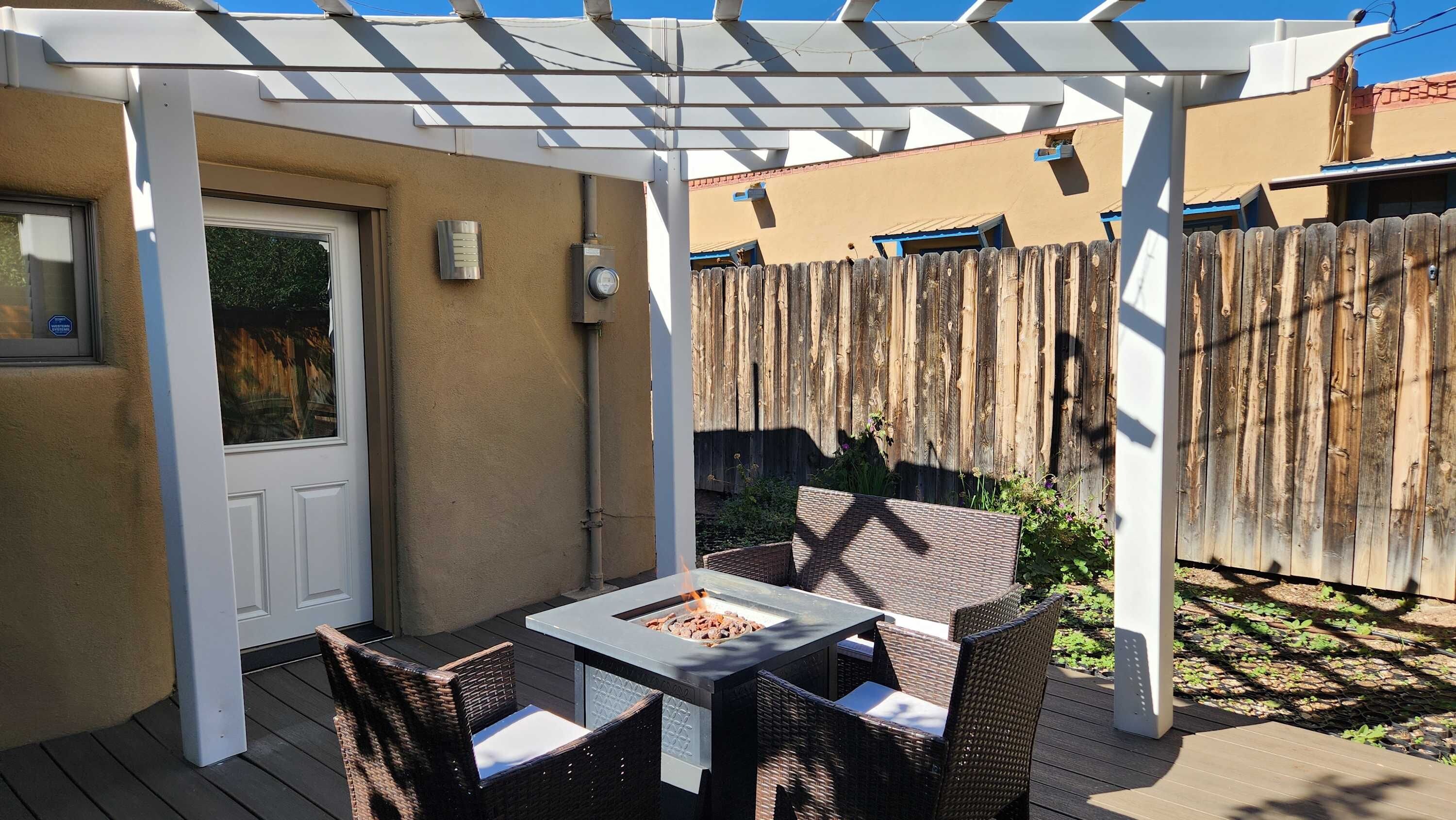 Eine Terrasse im Freien mit einer Pergola, einer Feuerstelle und Korbmöbeln.