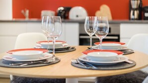 Una mesa de comedor dispuesta con platos y vasos, con una decoración en tonos rojo y blanco.