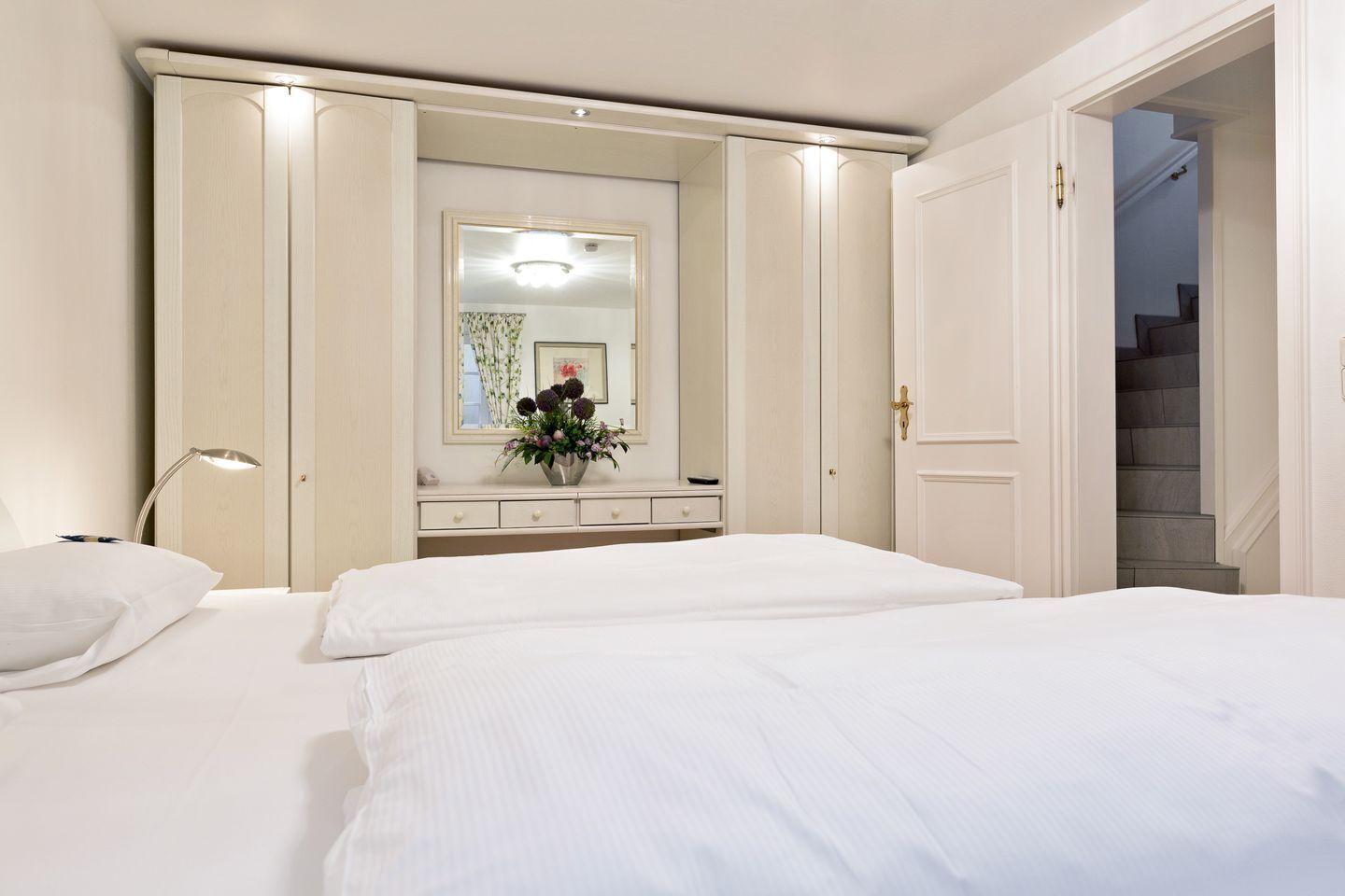 Een hotelkamer met twee bedden, een kaptafel, een spiegel en een trap.