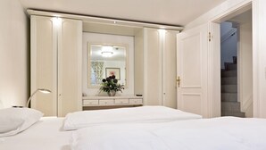 A hotel room with two beds, a dresser, a mirror, and a staircase. - Meeresbrise, App. 1 - Feines Wohnen mit Viel Platz Unter Kuscheligem Reet in Bestlage (Wenningstedt-Braderup (Sylt))