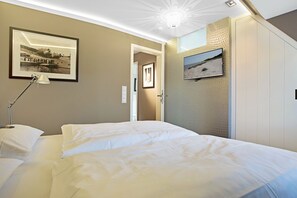 Une chambre d’hôtel avec un grand lit, un bureau avec une lampe, un tableau encadré au mur et une vue sur la plage par la fenêtre.