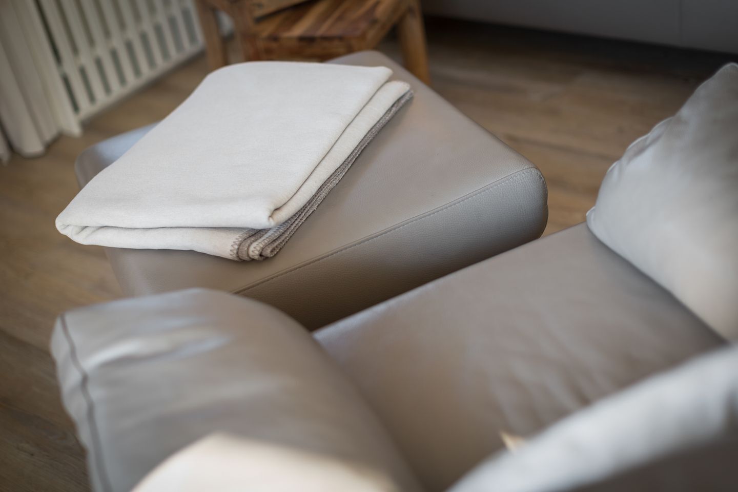 Parte de una habitación con un sofá de color claro y una manta blanca doblada.
