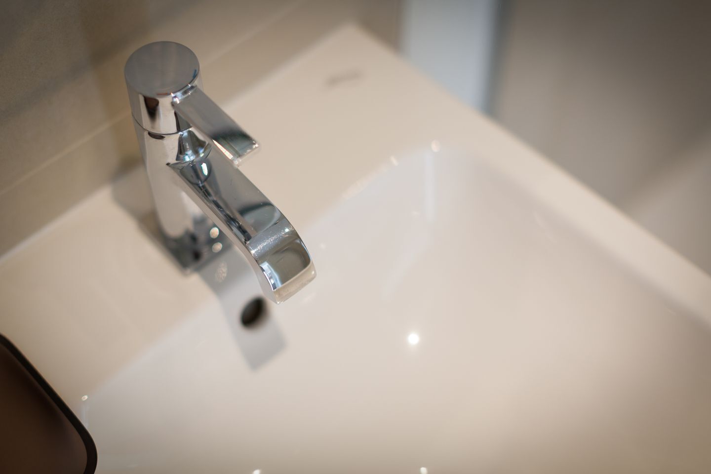 Un lavabo de salle de bain avec un robinet chromé et un plan de toilette blanc.