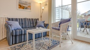 A living room with a striped sofa, a white coffee table, and a wicker chair.