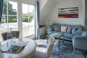 Un salon avec un canapé, une table basse et une table à manger, ainsi que des verres et un menu.