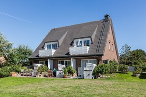 A two-story house with a sloped roof, a chimney, and a small balcony.