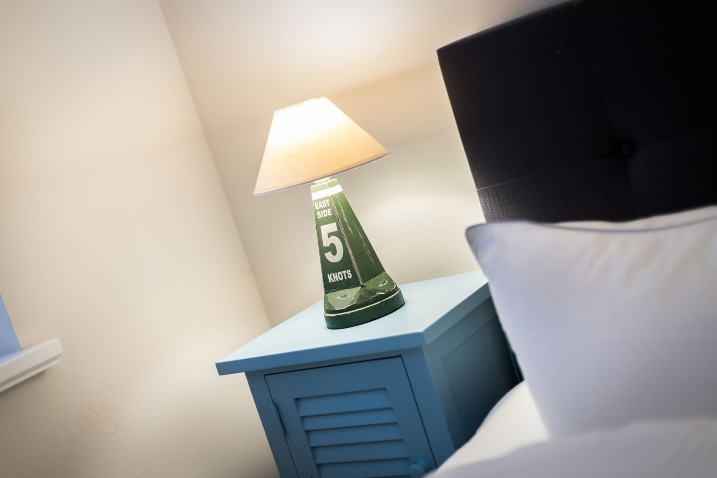 A bedside table with a lamp and a pillow.
