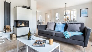 A modern living room with a fireplace, a grey sofa, and a coffee table with a magazine.