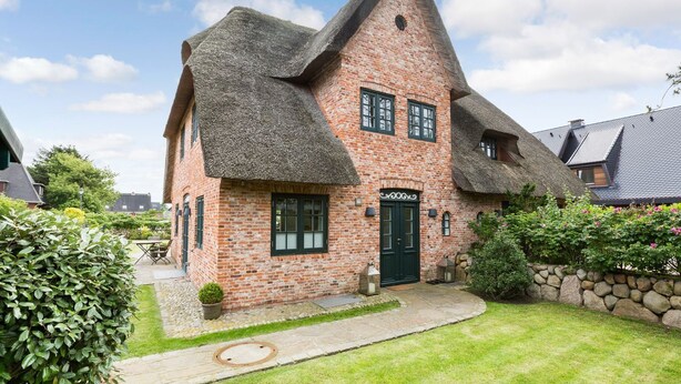 A traditional brick house with a steeply pitched thatched roof, a stone foundation, and a small front garden. - Watthüs Wenningstedt - Wenningstedter Superlativ (Wenningstedt-Braderup (Sylt))