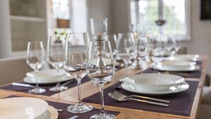 A dining table set with multiple wine glasses, plates, and cutlery, indicating a formal dining arrangement. - Watthüs Wenningstedt - Wenningstedter Superlativ (Wenningstedt-Braderup (Sylt))