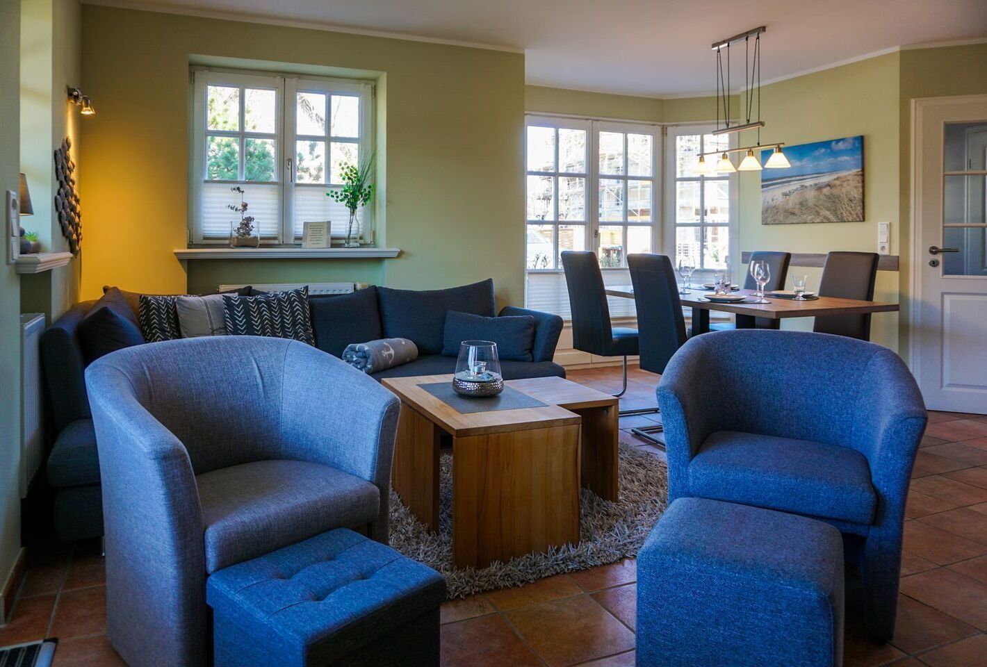Ein Wohnzimmer mit einer Sofagarnitur, einem Couchtisch und einem Essbereich mit Stühlen und einem Tisch.