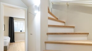 A modern interior with a staircase, a bed, and a window with curtains. - Landhaus Weidenstieg, App. 2 - Luxus und Wohlfühlen am Dorfteich (Wenningstedt-Braderup (Sylt))