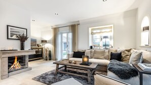 Ein modernes Wohnzimmer mit Kamin, einer Sofagarnitur, einem Couchtisch und einem Essbereich mit einer Lampe.