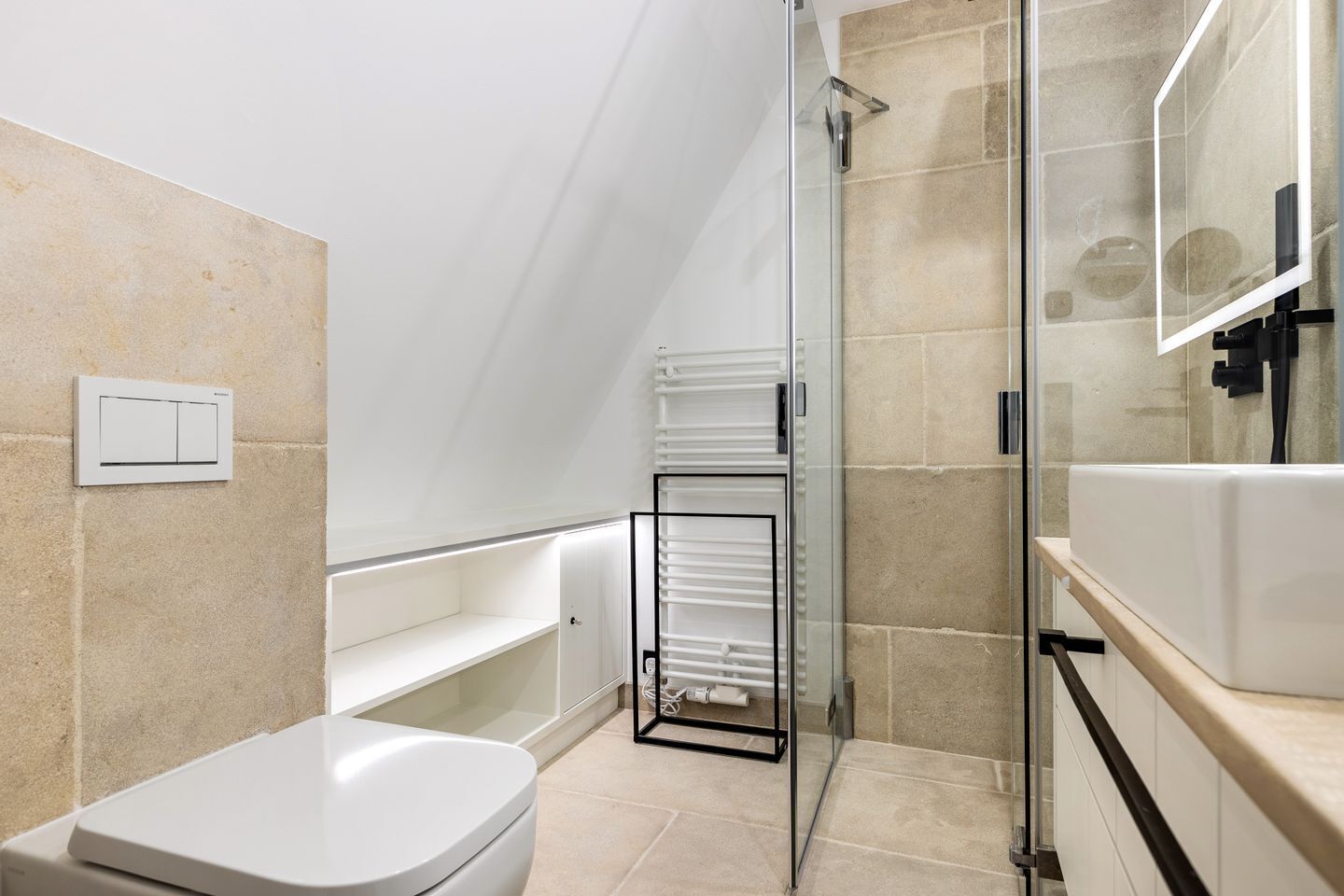 A modern bathroom with a toilet, a glass shower enclosure, a white sink, and a towel rack.